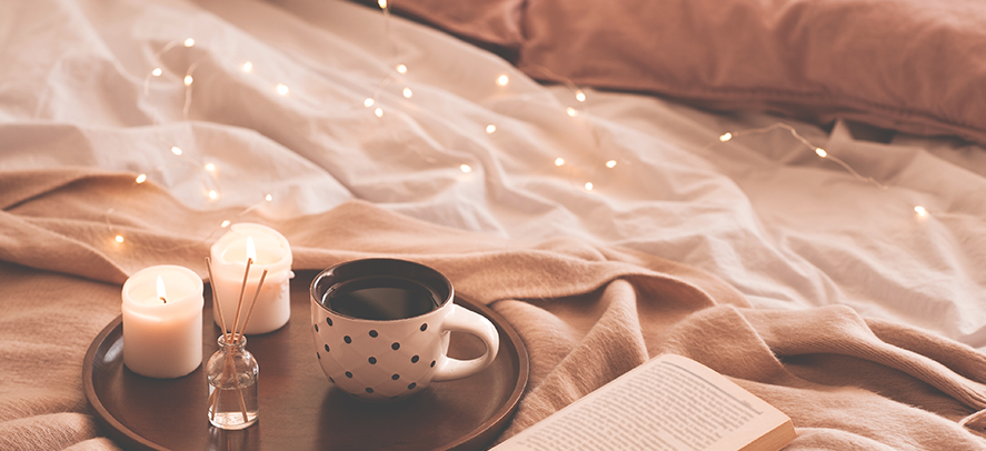 A cosy setting with fairy lights, scented reeds, candles, a cup of tea and a good book in bed.